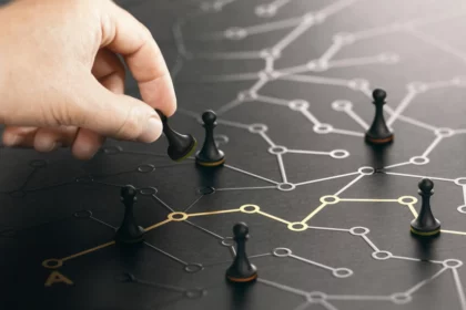 Dłoń umieszczająca pionka w złożonej, ciemnej sieci połączonych punktów danych i relacji, stanowiąca metaforę ujednoliconego profilu klienta i platformy Customer Data Platform.