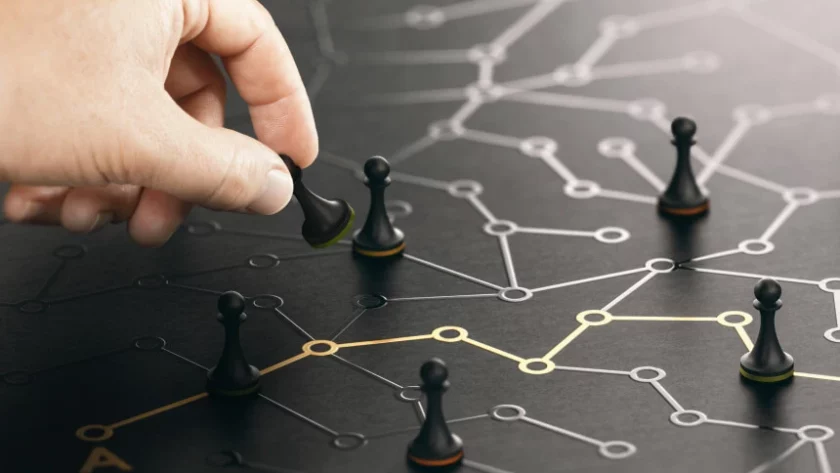 Dłoń umieszczająca pionka w złożonej, ciemnej sieci połączonych punktów danych i relacji, stanowiąca metaforę ujednoliconego profilu klienta i platformy Customer Data Platform.