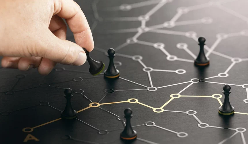 Dłoń umieszczająca pionka w złożonej, ciemnej sieci połączonych punktów danych i relacji, stanowiąca metaforę ujednoliconego profilu klienta i platformy Customer Data Platform.